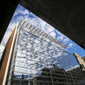 Glass exterior of Brodhead Center with blue sky and clouds reflecting in the windows